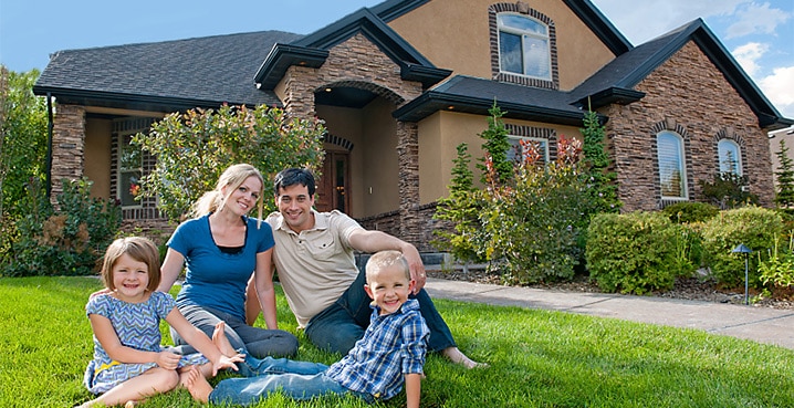 Happy family in the front yard of their home with new roof because of a roofing insurance claim turned out favorable.
