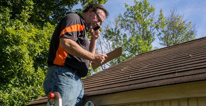 Man-on-ladder-doing-roofing-estimate-for-insurance-roofing-claims