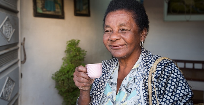 Happy woman drinking tea because residential roof repairs gave her peace of mind